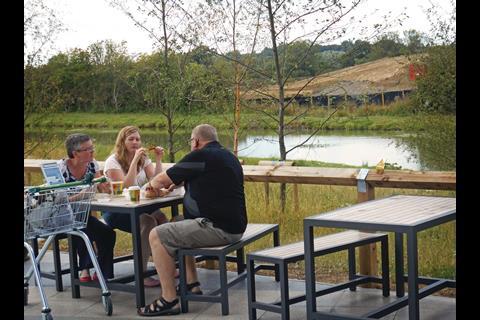 Just beyond the canopy at the entrance to the new Waitrose on the outskirts of Swindon there are wooden and metal tables and benches.
